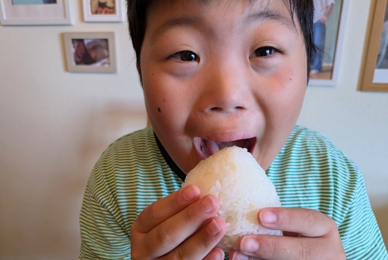 どろんこ米のおにぎりを頬張る希さん
